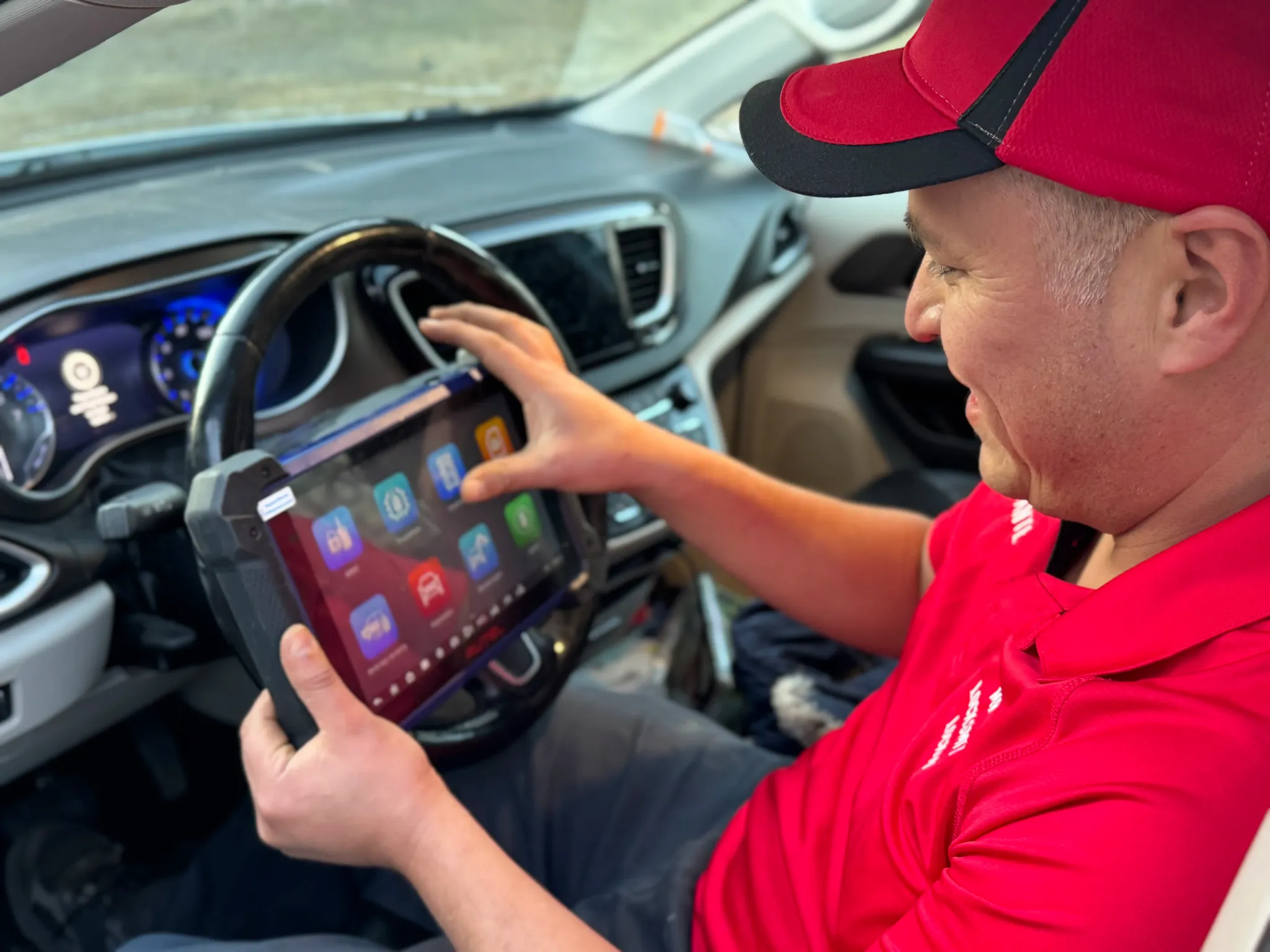 Dante Salcedo using a professional diagnostic tablet to program a key fob inside a vehicle